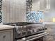Close-up of stainless steel stove with designer tile backsplash and light gray cabinets in a modern kitchen at 1655 Scotland Ave, Charlotte, NC 28207