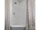 Stand up shower features white tub with white and gray marble walls and geometric patterned shower curtain at 1655 Scotland Ave, Charlotte, NC 28207