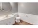 Well-lit bathroom with vanity, toilet, wood-look flooring, round mirror, and wainscotting at 2605 Willowdale Ln, Matthews, NC 28105