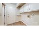 Bright laundry room featuring a door, upper cabinets, utility sink and wood-look flooring at 2605 Willowdale Ln, Matthews, NC 28105