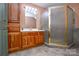 Bathroom with wood cabinets, corner shower, and tile floor at 5839 Painted Fern Ct, Charlotte, NC 28269