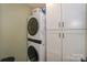 Stackable washer and dryer with white shaker cabinets for storage, creating an organized space at 18631 Vineyard Point Ln, Cornelius, NC 28031