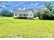Back exterior view of a white, two-story house with a covered porch overlooking an expansive green yard at 5037 Faith Rd, Salisbury, NC 28146