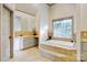Inviting bathroom with a soaking tub surrounded by tile, separate vanities, and plenty of storage at 2425 Birdie Ne Ln, Conover, NC 28613