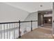 Carpeted upstairs hallway featuring decorative black and white railings with view of front door and staircase at 2425 Birdie Ne Ln, Conover, NC 28613
