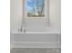 A large tub is set beneath a window, next to gray tile floors at 3110 Westerwood Dr, Charlotte, NC 28214