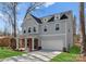 A two-story home with gray siding, red brick porch, and a long driveway leading to an attached garage at 3110 Westerwood Dr, Charlotte, NC 28214