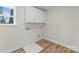 Bright laundry room featuring wood floors, a window with natural light, and white cabinets at 3110 Westerwood Dr, Charlotte, NC 28214