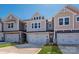 View of craftsman-style townhomes showcasing neutral exteriors, garage doors, and well-manicured lawns under a clear blue sky at 161 Halite Ln, Waxhaw, NC 28173