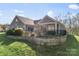 View of home's rear exterior featuring a well-kept lawn and a stone retaining wall at 1236 Avalon Pl, Matthews, NC 28104