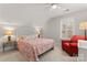 Bedroom featuring a coral bedspread, shuttered windows, ceiling fan, red chair, and bedside lamps at 1236 Avalon Pl, Matthews, NC 28104