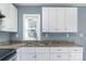 Close up of sink, faucet and granite counters in a kitchen with white cabinetry and a view from the window at 2630 Druid Hills Way, Charlotte, NC 28206