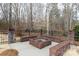 Outdoor brick fire pit with built-in seating surrounded by a black metal fence and wooded backdrop at 1038 Rolling Park Ln, Fort Mill, SC 29715