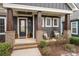 Inviting front porch with wood columns, brick bases, seating, and an elegant black front door at 112 Sisters Cove Ct, Mooresville, NC 28117