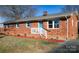 Brick ranch house with blue shutters, white steps, and landscaping at 31655 Pinewood Dr, New London, NC 28127