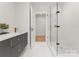 Modern bathroom featuring a glass shower, gray cabinets with gold fixtures, and white tile floors at 4026 Chevington Rd # 102, Charlotte, NC 28226