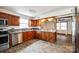 Galley kitchen with stainless steel appliances, wood cabinetry, and granite counters; view to living room at 110 Yorktowne St, Fort Mill, SC 29715