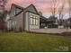 An exterior view of a home featuring a stone patio and green lawn during a colorful dusk at 116 Hunt Camp Trl # 11, Davidson, NC 28036