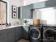 Functional laundry room featuring gray cabinets, a sink, modern washer and dryer, and a window for natural light at 116 Hunt Camp Trl # 11, Davidson, NC 28036