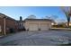 Rear view of the house featuring an attached two-car garage with tan siding and ample parking space at 1308 Princeton Ave, Gastonia, NC 28054