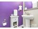Stylish half bathroom featuring a pedestal sink, decorative mirror, and purple accent wall at 4146 La Crema Dr, Charlotte, NC 28214