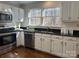 Bright kitchen features stainless steel appliances, granite counters, white cabinets, and a large window at 9709 Calpher Ct, Matthews, NC 28105