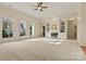 Sunlit living room with plush neutral carpet, a fireplace, and large windows providing plenty of natural light at 10302 Sawtimber Ct, Huntersville, NC 28078