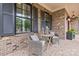 Brick porch with gray wicker chairs and a wooden table, creating a relaxing space at 1117 Churchill Commons Dr, Charlotte, NC 28211