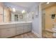 Well-lit bathroom featuring double sinks, modern fixtures, and a separate shower room with tiled flooring at 15215 Timberview Ln, Huntersville, NC 28078
