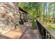 Exterior shot of the back deck featuring outdoor furniture, a stone wall, and lush greenery at 15215 Timberview Ln, Huntersville, NC 28078