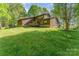 Expansive lawn and charming exterior with brown siding, stone accents, and a rear deck create an inviting outdoor space at 15215 Timberview Ln, Huntersville, NC 28078