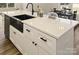 Detailed view of the kitchen island featuring white cabinets, a black sink, and quartz countertops at 625 Charles St, Rockwell, NC 28138