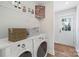 Bright laundry room with white washer and dryer, shelving, and a rear entry door at 625 Charles St, Rockwell, NC 28138