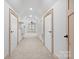 Long hallway with carpet and white walls leads to bedrooms and bathrooms with a ceiling fan at the end at 917 Patrick Johnston Ln, Davidson, NC 28036