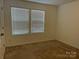 Empty bedroom with two windows and neutral colored carpet at 9514 Currier Rd, Charlotte, NC 28215