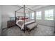 Well-lit bedroom with large windows, a four-poster bed, and a stylish bench at the foot at 5680 Clear Creek Ln, Charlotte, NC 28215
