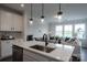 Well-lit kitchen island featuring modern pendant lights, stainless steel dishwasher and a sink with dark faucet at 5680 Clear Creek Ln, Charlotte, NC 28215
