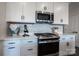 Close-up of the kitchen showcasing stainless steel microwave, a range, and white cabinets with dark handles at 5680 Clear Creek Ln, Charlotte, NC 28215