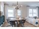 Stylish dining area adjacent to the living room featuring a modern chandelier, round table, and ample natural light from large windows at 14042 Aikenwood Dr, Charlotte, NC 28278