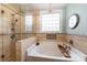 Relaxing bathroom featuring soaking tub with tiled surround, glass block window, and modern fixtures at 4008 Saphire Ln, Indian Trail, NC 28079