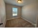 A cozy bedroom featuring neutral walls, carpeted flooring, and a window for natural lighting at 5544 Stafford Rd # 30, Charlotte, NC 28215