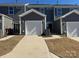 View of gray townhomes with attached garages, concrete driveway, and manicured lawns at 5544 Stafford Rd # 30, Charlotte, NC 28215