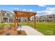 View of community pergola and bench seating area with landscaping and sidewalks connecting attractive townhome exteriors at 5548 Stafford Rd # 29, Charlotte, NC 28215