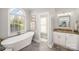 Bright bathroom featuring a soaking tub next to a large arched window and vanity area at 180 Sink Farm Rd, Mooresville, NC 28115