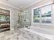 This is a primary bathroom featuring a marble tile floor, glass shower, soaking tub, and large window at 3227 Pinehurst Pl, Charlotte, NC 28209