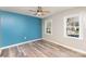 Bedroom with two windows, blue accent wall, wood-look floors, and gray walls at 5328 Caradon Dr, Charlotte, NC 28227