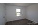 Cozy carpeted bedroom with a window, white walls, and a closed door at 2608 Clipper Nw Ct, Concord, NC 28027