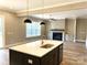 Modern kitchen with a central island, stainless steel sink, and open views of the living room and fireplace at 143 Dabbling Duck Cir, Mooresville, NC 28117