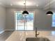 Modern kitchen island with stainless steel sink and views of the sliding glass doors and the outdoor deck at 143 Dabbling Duck Cir, Mooresville, NC 28117