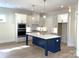 Bright kitchen with white cabinetry, navy island, modern appliances, and stylish pendant lighting at 148 Dabbling Duck Cir, Mooresville, NC 28117